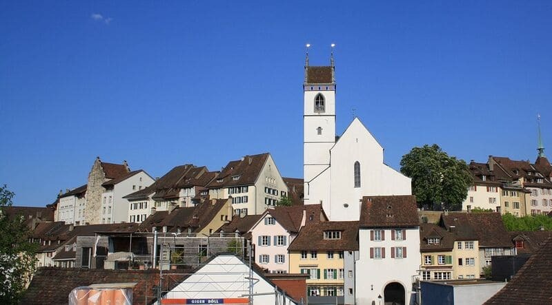 Altstadt von Aarau mit weißer Kirche, dicht stehenden Häusern und klarem Himmel.