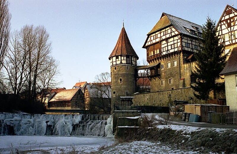 Mittelalterliche Fachwerkbauten und Rundturm über einem kleinen Wasserfall im winterlichen Balingen.