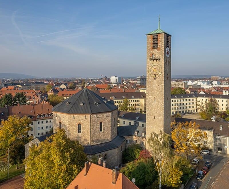 Rundkirche und markanter Turm in Bamberg, eingebettet in herbstliche Stadtlandschaft.