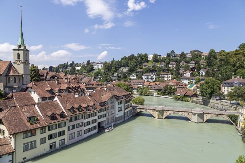 Blick über die Berner Altstadt mit Aarefluss, historischer Brücke und dicht bebauten Häusern.
