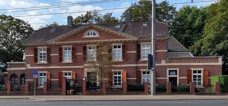 Zweistöckiges Backsteingebäude in Bochum mit zentralem Eingang und umlaufender Mauer.