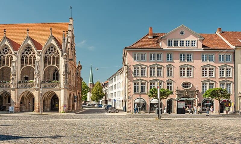 Historische Gebäude am Braunschweiger Platz mit gotischem Rathausanbau und hellen Fassaden im Sonnenschein.