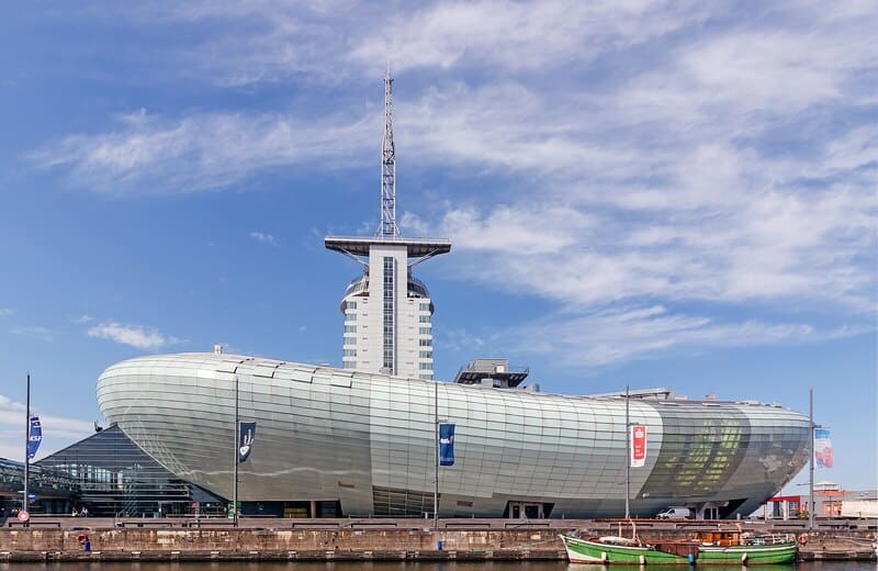 Futuristisches Klimahaus in Bremerhaven mit geschwungener Glasfassade und hohem Turm am Hafenbecken