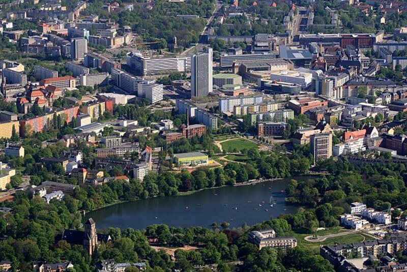 Weitblick über Chemnitz mit Hochhäusern, Wohngebäuden und grünem See umgeben von Bäumen.