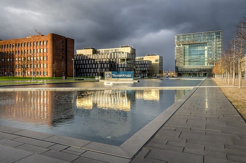 Moderne Bürogebäude am ThyssenKrupp-Campus in Essen mit großem Wasserbecken im Vordergrund.