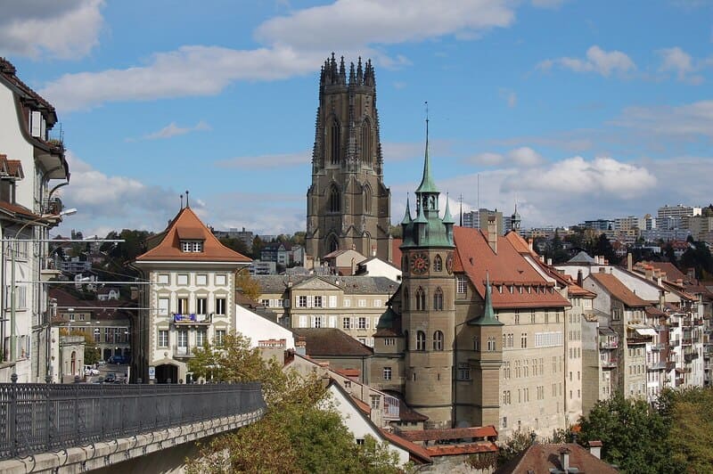 Stadtansicht von Freiburg im Üechtland mit markantem Münster und historischen Gebäuden unter blauem Himmel.