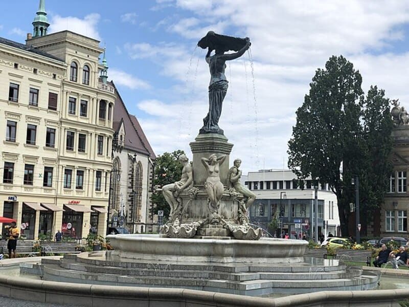 Brunnenanlage in Görlitz mit figurengeschmücktem Wasserspiel und umliegenden historischen Gebäuden.