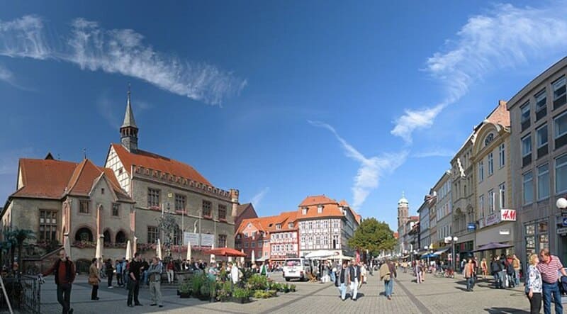 Belebter Marktplatz in Göttingen mit historischem Rathaus, Fachwerkhäusern und vielen Passanten.