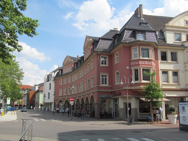 Blick auf farbige Altstadtfassaden in Gütersloh mit Fußgängern und Außengastronomie.