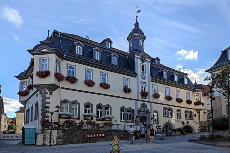 Historisches Rathaus von Ilmenau mit Turm und Blumenfassaden bei sonnigem Himmel.