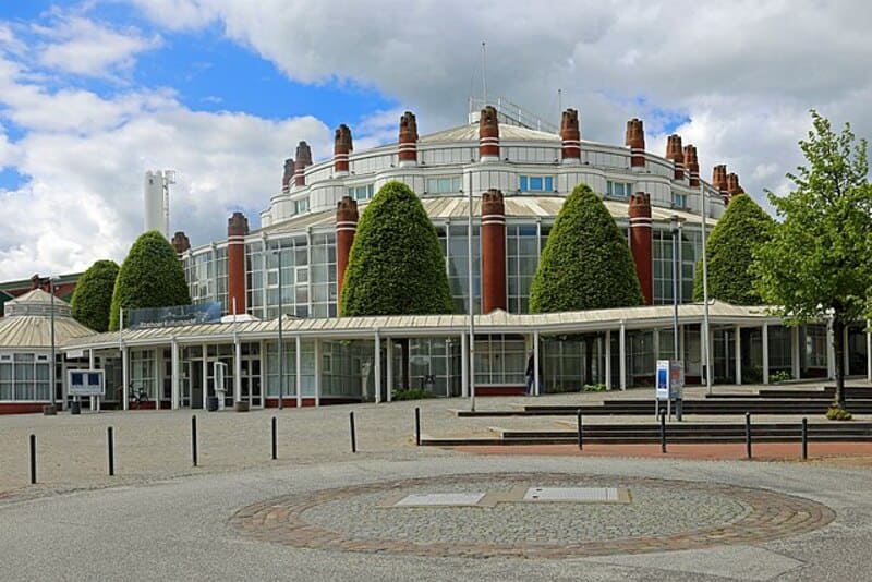 Moderner Gebäudekomplex in Itzehoe mit großen Glasflächen und symmetrisch angeordneten Formbäumen.