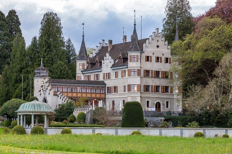 Historische Villa mit Türmen und Gartenanlage in Kreuzlingen, Schweiz, umgeben von Bäumen und Wiese.