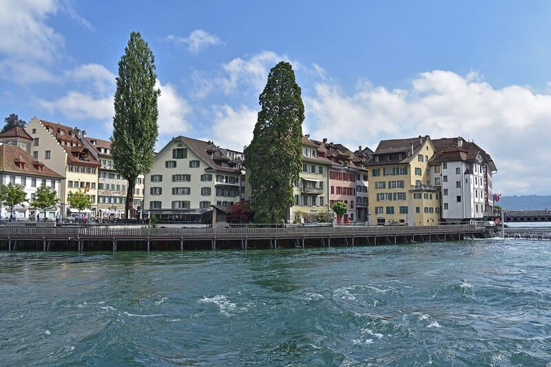 Altstadt von Luzern mit farbigen Häusern direkt an der Reuss und ruhigem Flusswasser.