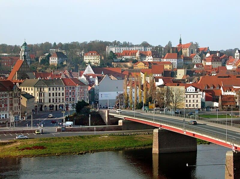 Blick auf Meißen mit roter Altstadtdachlandschaft, Brücke über die Elbe und historischem Stadthügel.