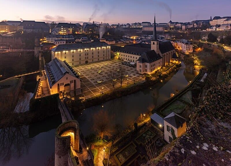 Weitwinkelansicht von Neumünster mit Kirche, Innenhof und umliegenden Häusern im warmen Abendlicht.