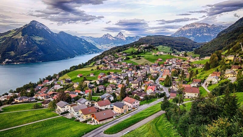 Wohnhäuser in Nidwalden vor eindrucksvoller Bergkulisse und dem ruhig liegenden See.