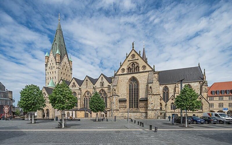 Große historische Kirche mit hohem Turm und weitläufigem Platz im Zentrum von Paderborn.