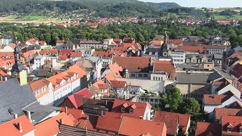 Panorama von Rudolstadt mit roten Dächern, Altstadtgassen und bewaldeten Hügeln im Hintergrund.