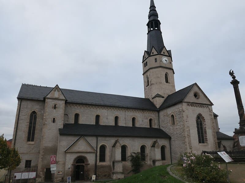 Historische Kirche in Sangerhausen mit hohem Turm, hellem Mauerwerk und schlichtem Eingangsbereich.