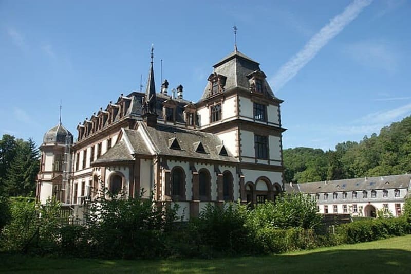 Historisches Schlossgebäude mit Türmen und Arkaden, umgeben von Grünflächen bei Sonnenschein in Sinzig.