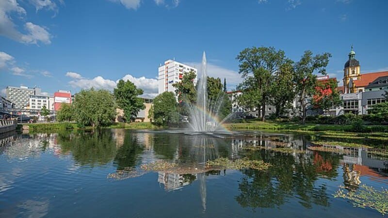 Springbrunnen im Stadtpark von Suhl mit hohem Wasserstrahl und Spiegelung im Teich.