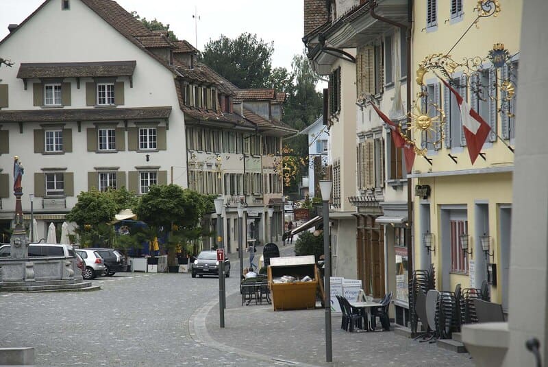 Gasse in der Altstadt von Sursee mit historischen Häusern, Cafétischen und Kopfsteinpflaster.