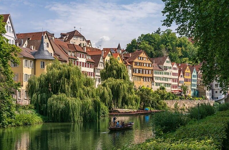 Bunte Altstadthäuser entlang des Neckars in Tübingen mit üppigen Weiden am Ufer.