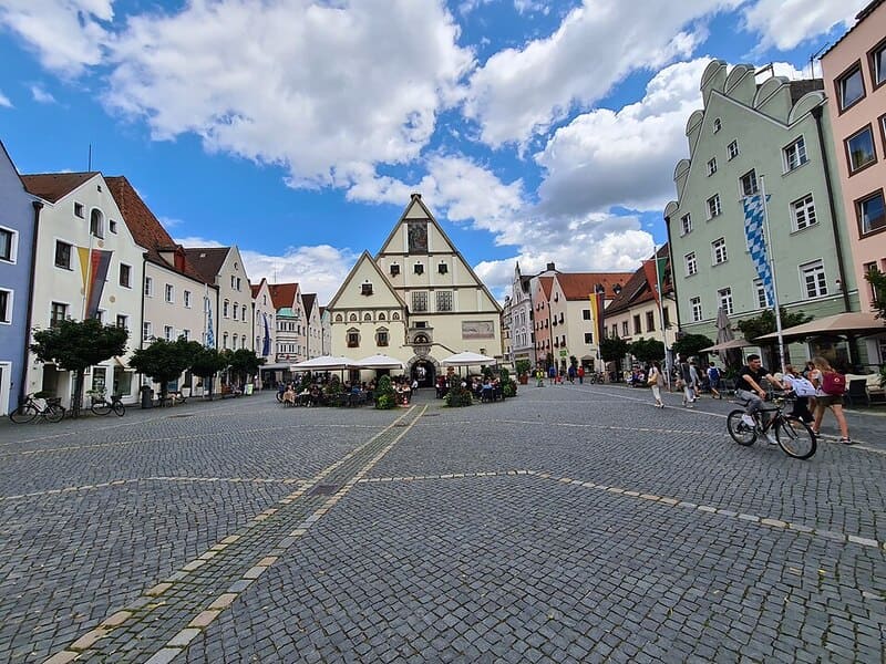Coreflow-Weiden-Hero Belebter Marktplatz in Weiden mit Giebelhäusern und zentralem historischen Gebäude unter Wolkenhimmel.