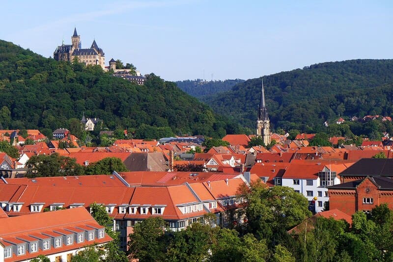 Coreflow-Wernigerode-Hero Blick über Wernigerode mit roten Dächern, bewaldeten Hügeln und dem Schloss auf einer Anhöhe