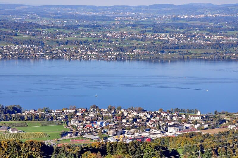 Panorama von Wetzikon, Schweiz, mit Wohngebiet, Feldern und Zürichsee im Hintergrund.