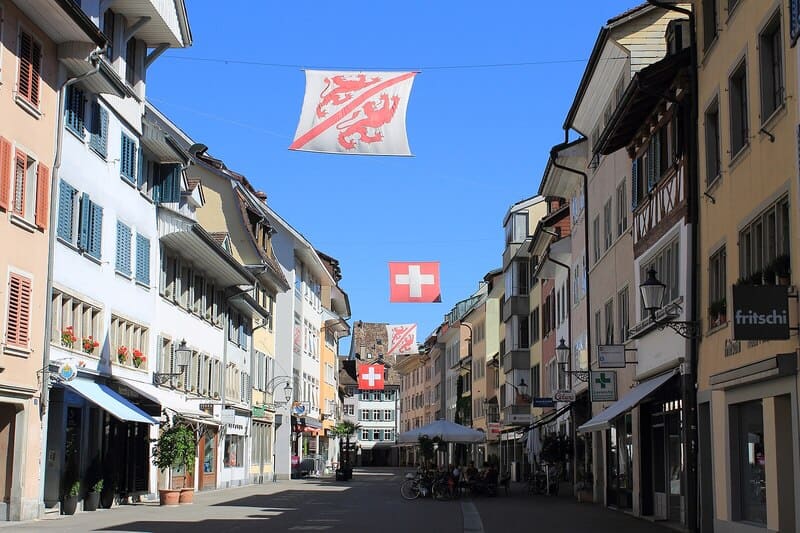 Altstadtstraße in Winterthur, Schweiz, mit historischen Häusern, Schweizer Fahnen und Cafés.