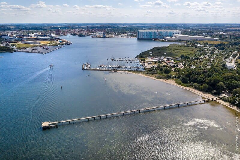 Luftaufnahme von Wismar mit langer Seebrücke, Küstenlinie, Yachthafen und weitläufigem Hafenbecken
